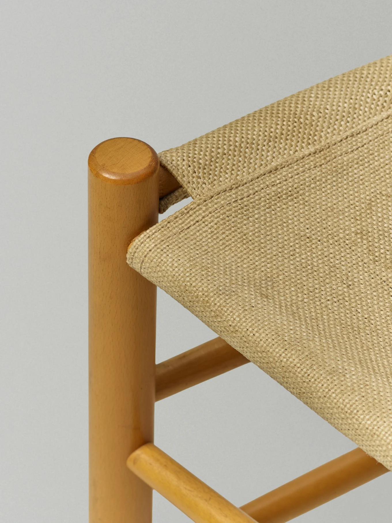 Nærbilde av en stol med lysebrun treramme og et flettet beige sete.