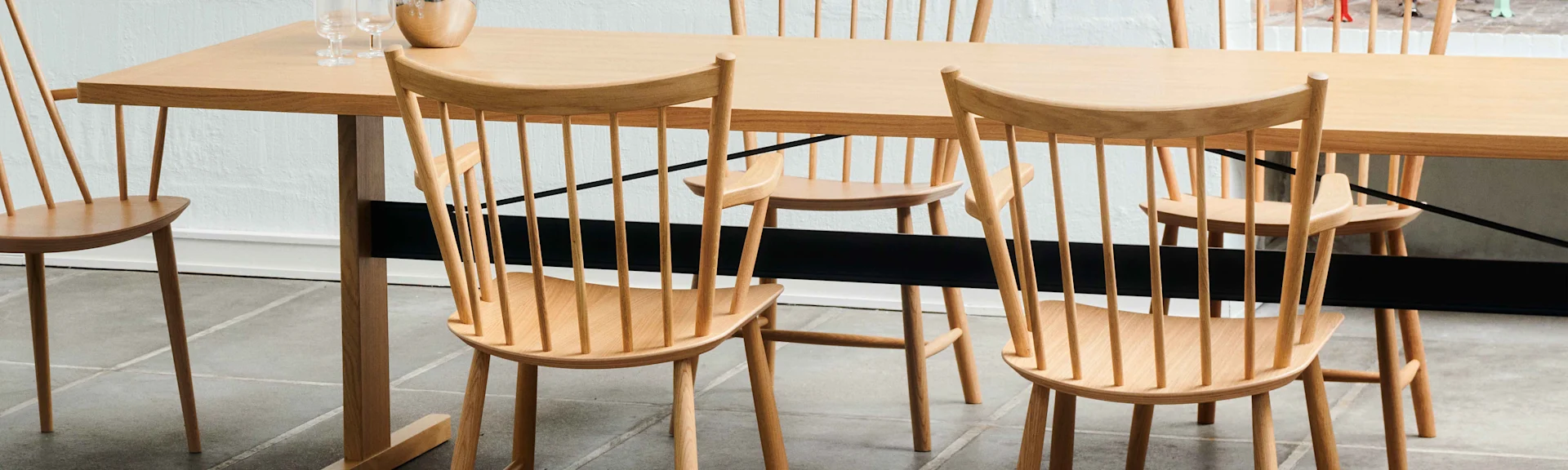 Lys tre spisebord med pinnestoler og glass på bordet.